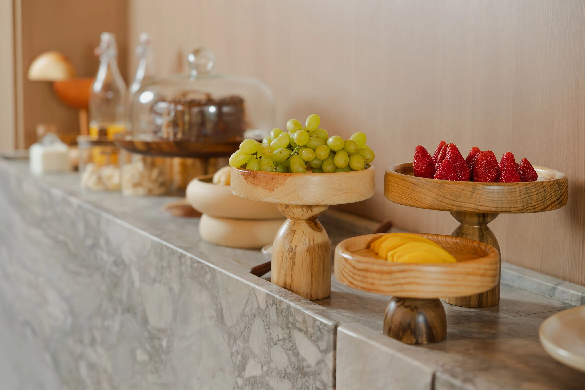 Frutas frescas no buffet do café — uvas, morangos e manga em pratos de madeira