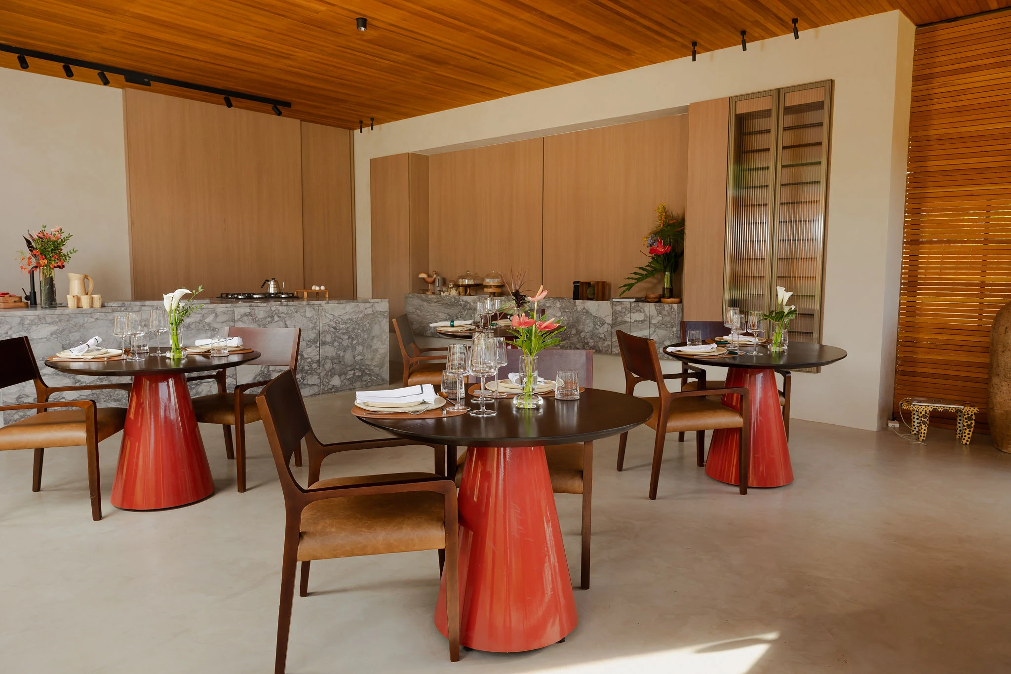 Salão do café com mesas em terracota e bancada de mármore