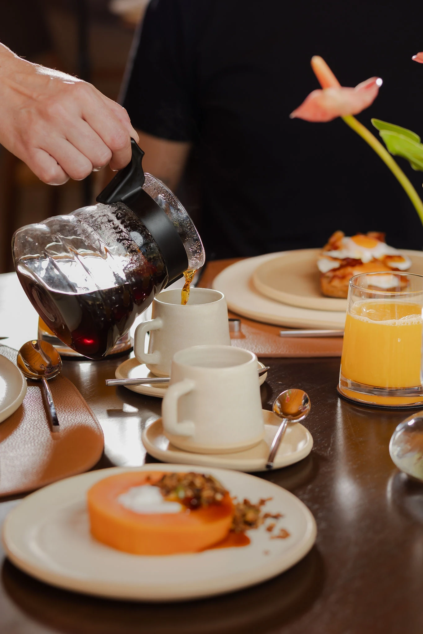 Café coado servido à mesa, com mamão com granola e suco de laranja